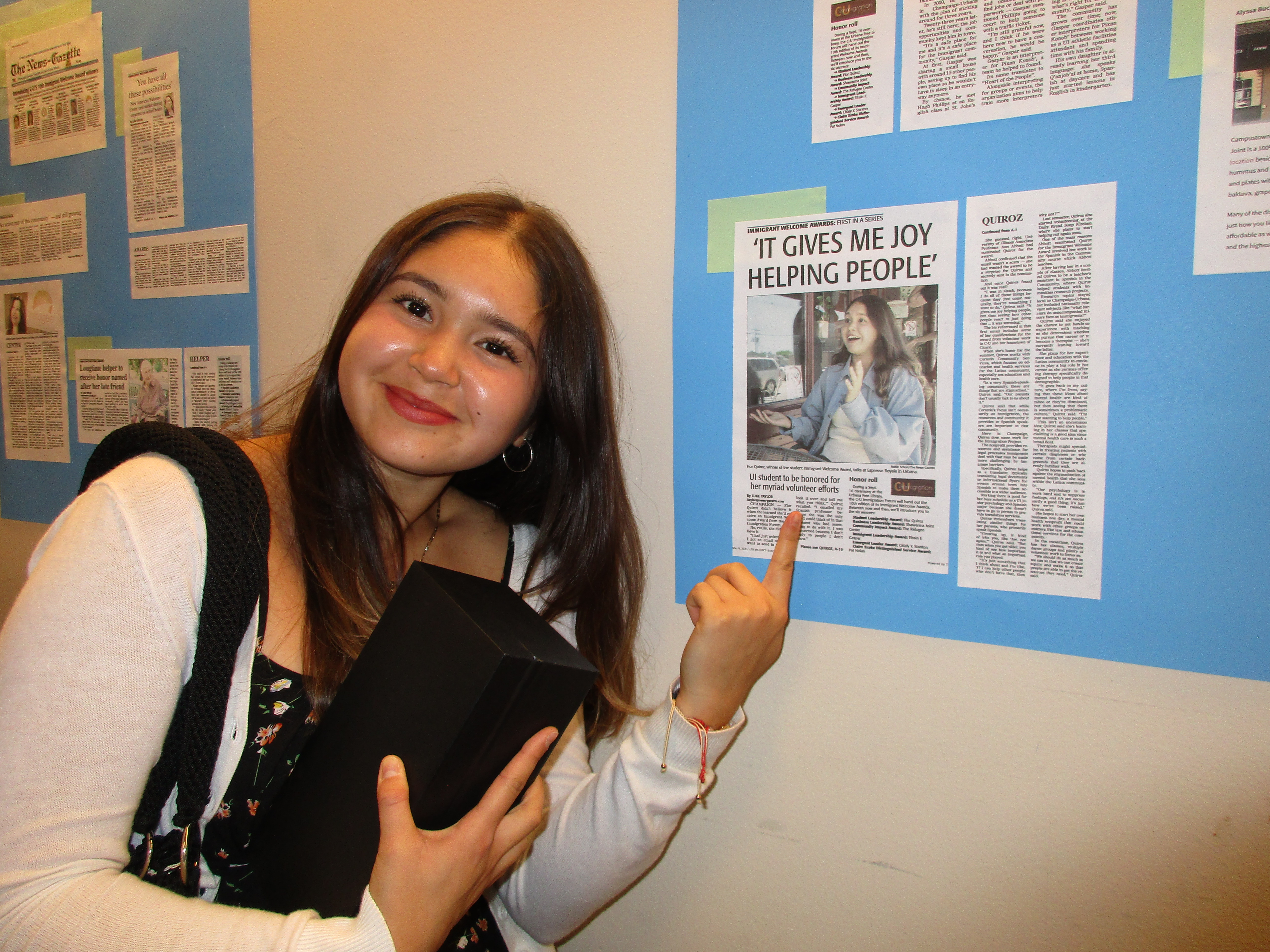 Flor Quiroz poses next to clipping of her News Gazette article